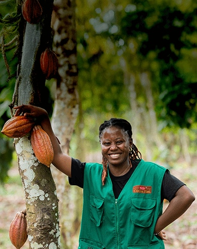 woman smiling next to cocoa tree